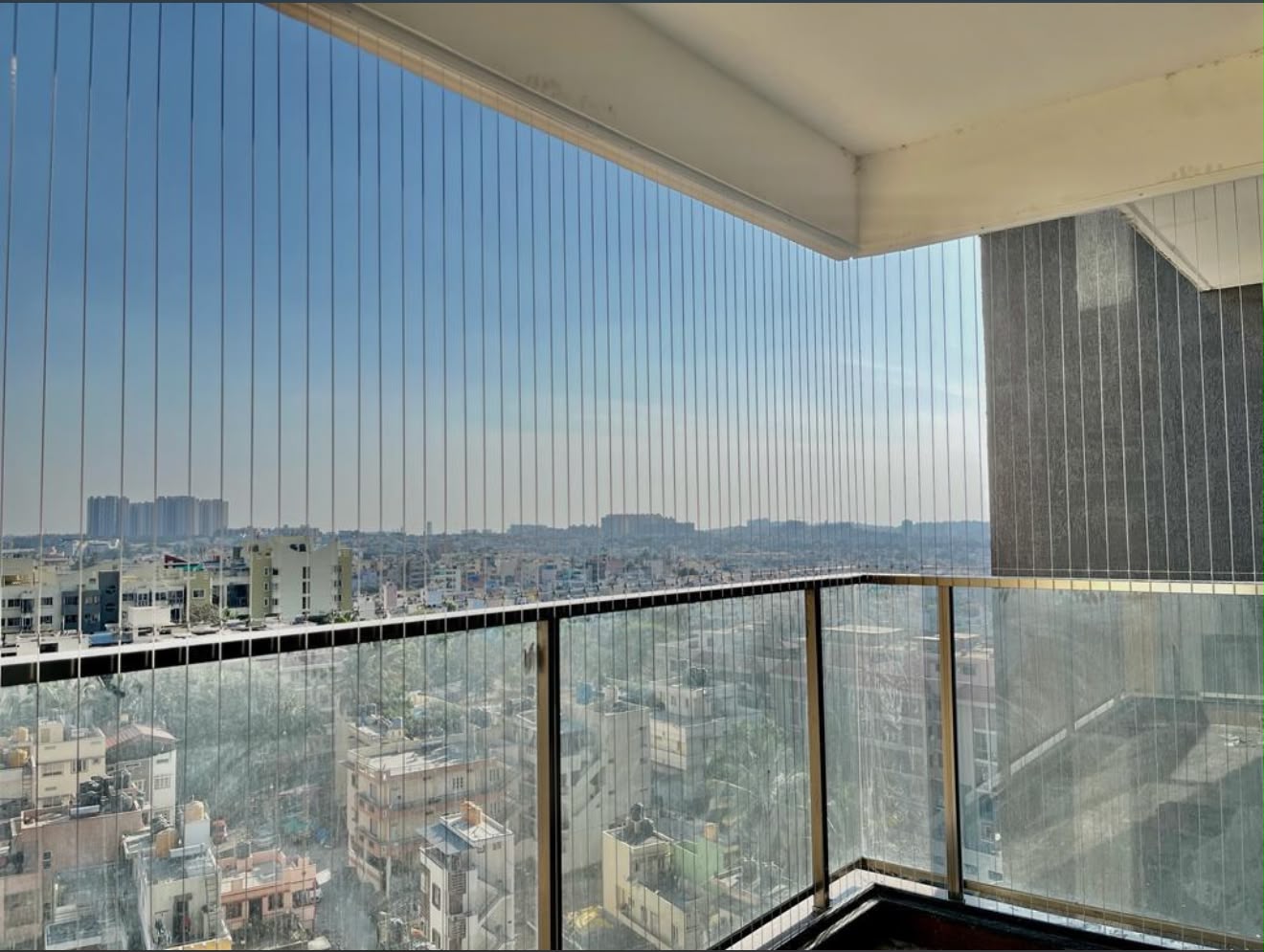 Invisible grille across a glass corner balcony with Bengaluru city view