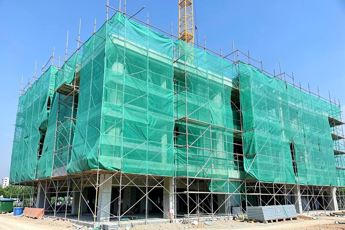 Building under construction wrapped in green construction safety netting